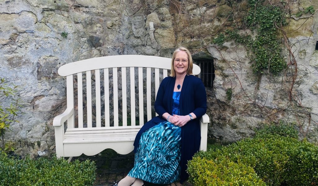 Fleur smiling on a bench in a local garden