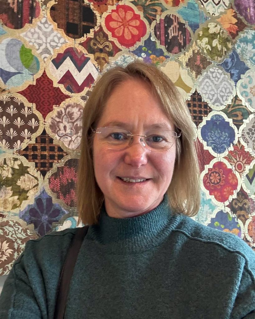 Fleur smiling in front of a patterned mosaic wall